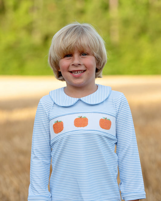 Child wearing a blue striped shirt with pumpkin design outdoors