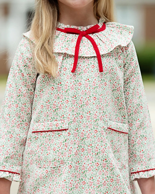 Child wearing a floral dress with a red collar and trim.