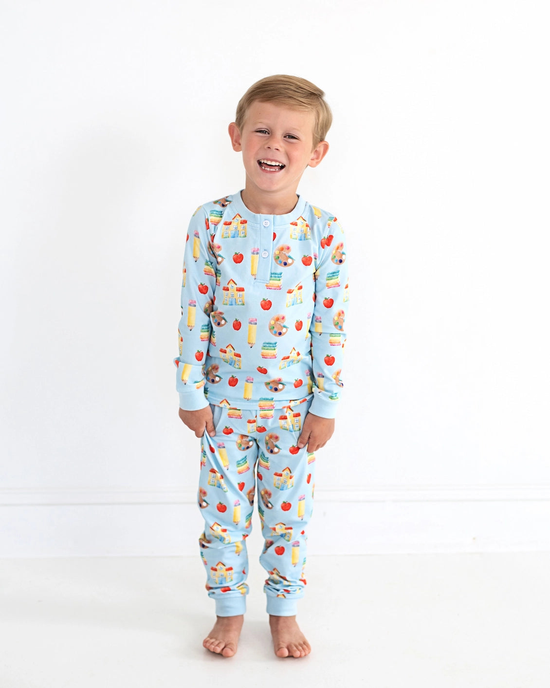 Child wearing blue pajamas with fruit pattern on a white background