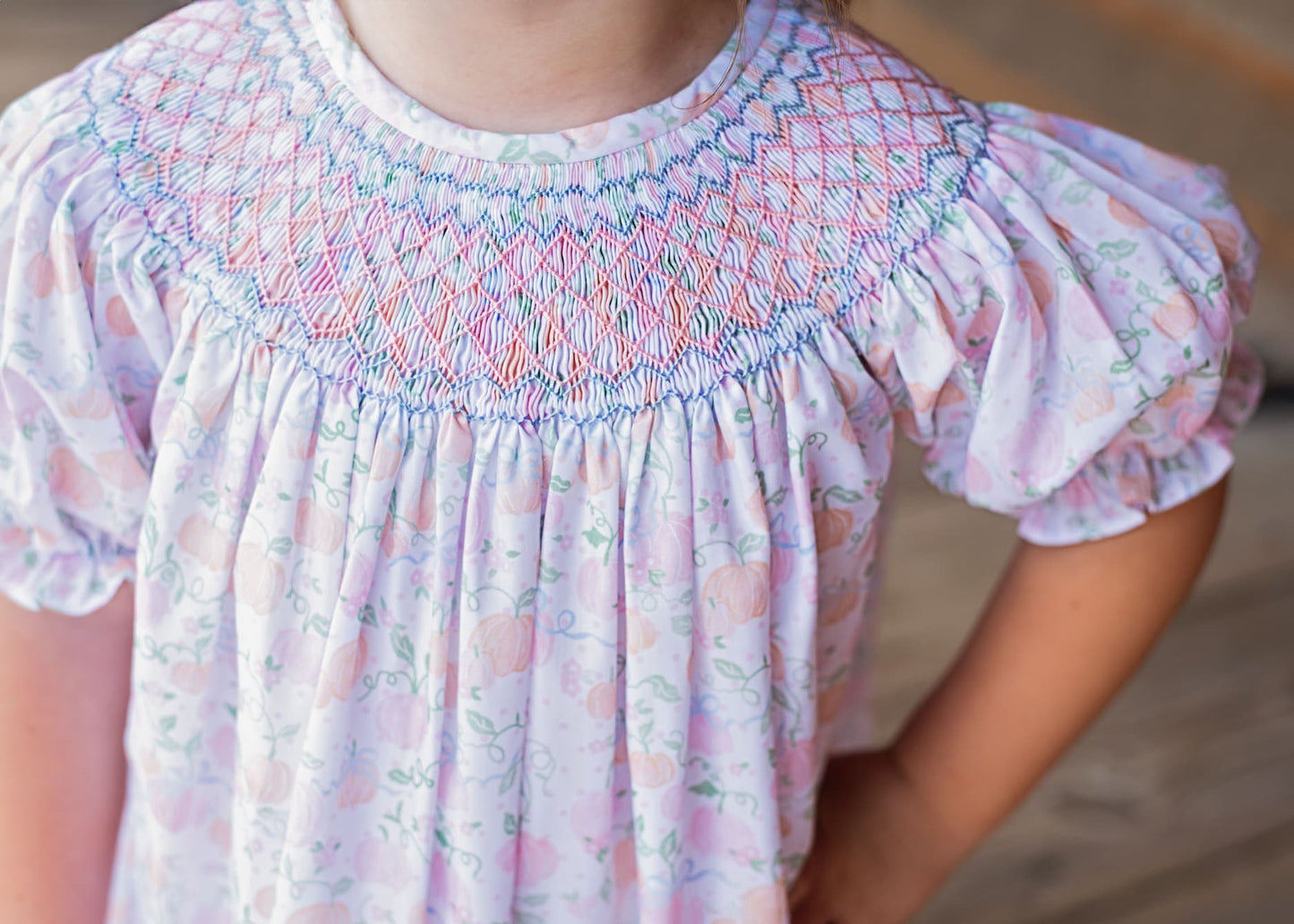 Close-up of a child's dress with smocked neckline and floral pattern.