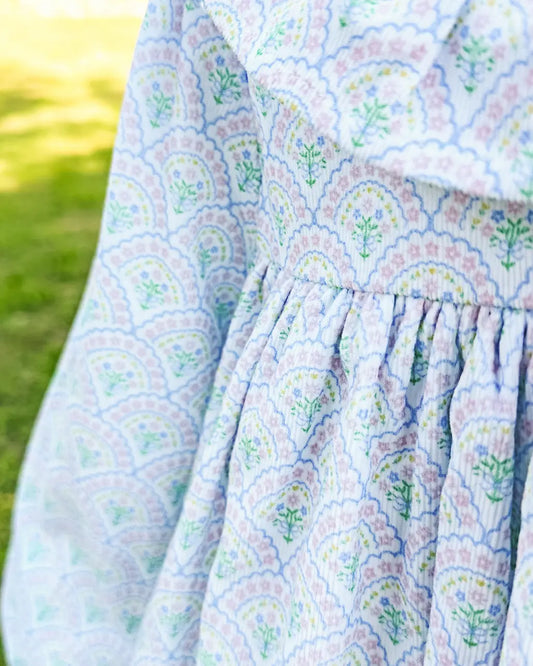Close-up of a floral-patterned fabric with a blurred green outdoor background