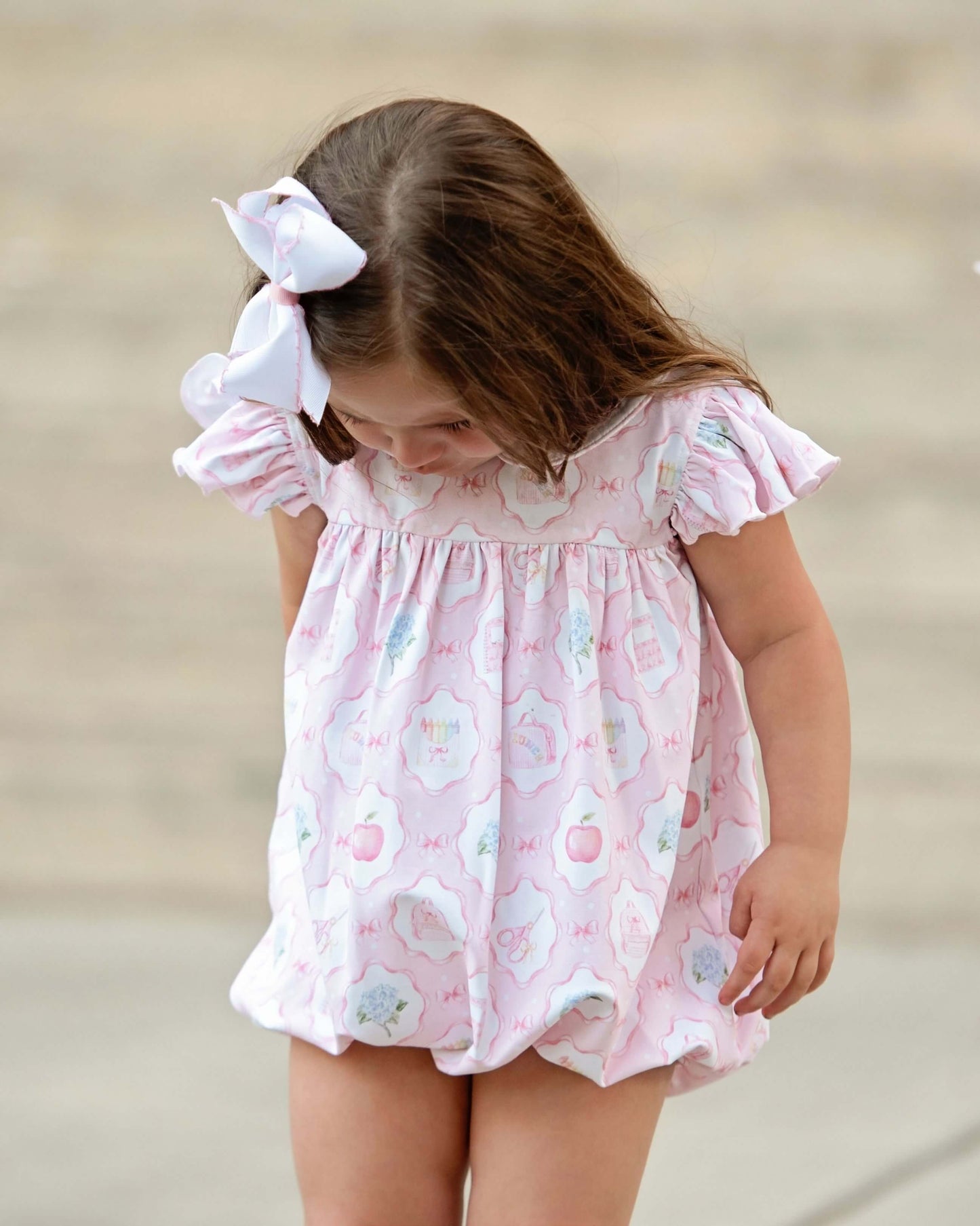 girl wearing bubble with school motifs looking down