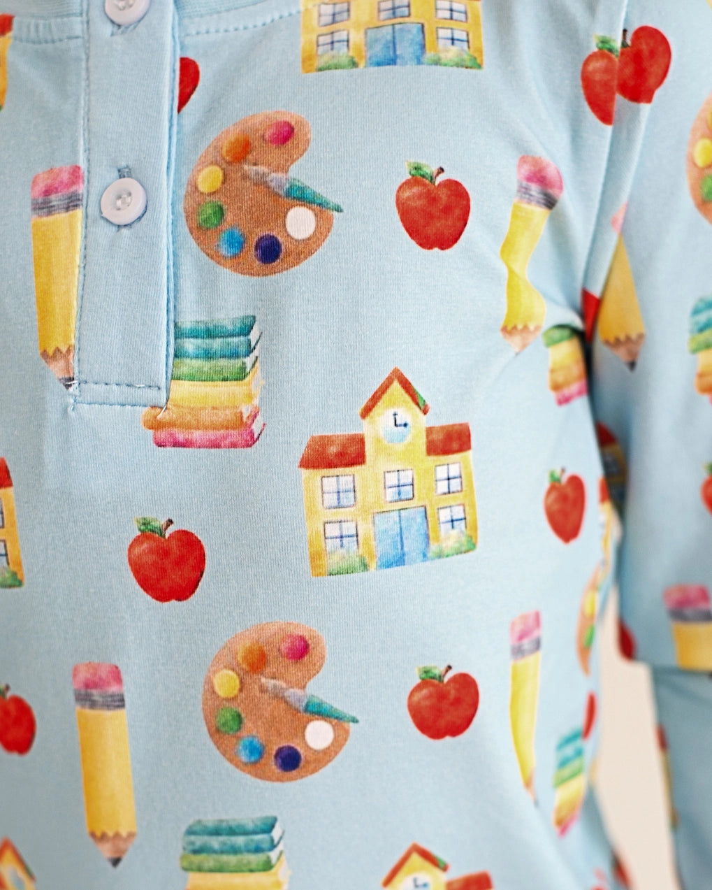 Light blue clothing with educational pattern including apples, books, and colorful pencils.