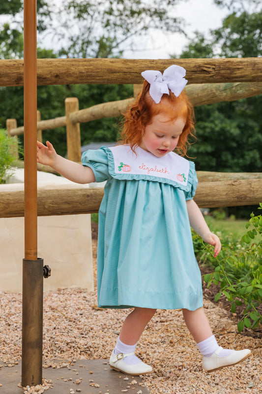 Girl wearing the Green Gingham Embroidered Pumpkin Dress with name personalization