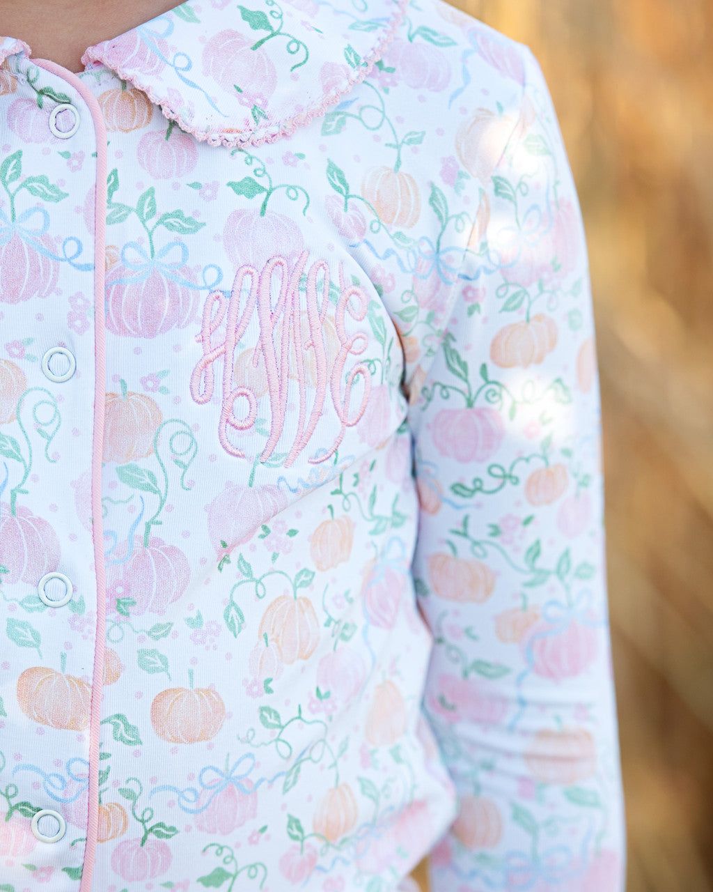 pajama set with floral and pumpkin  pattern and embroidered "hWe" on a blurred natural background