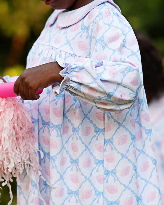 Person wearing a patterned garment with pink and blue design, holding a pink object.