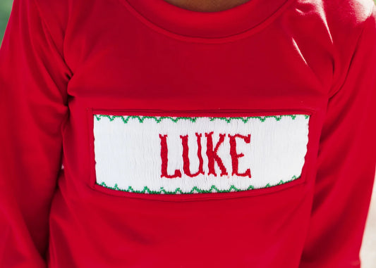 Red shirt with a name patch displaying 'LUKE' on a plain background