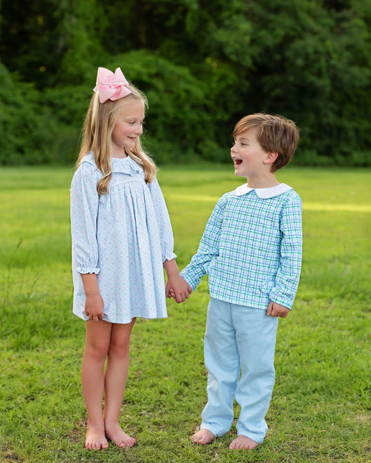 Two children holding hands in a grassy field