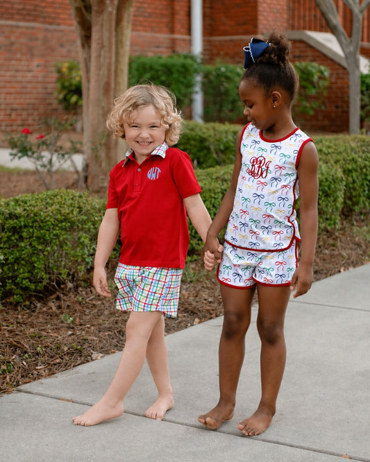 two children wearing coordinating outfits , holding hands on a sidewalk