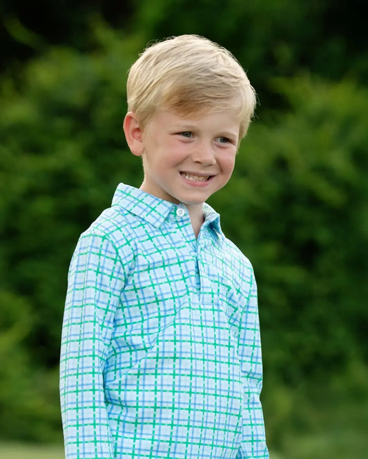 Young boy wearing a light blue and green checkered shirt against a blurred green background