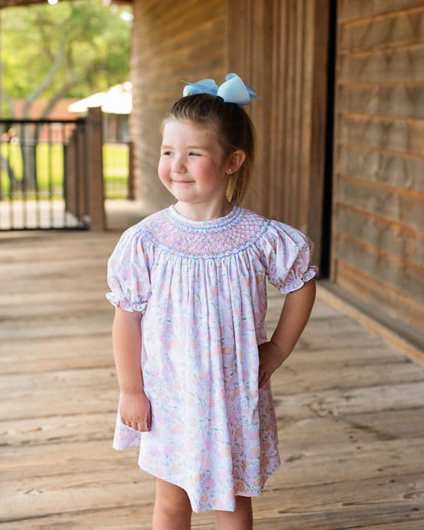 young-girl-in-a-floral-dress-standing-on-a-wooden-porch