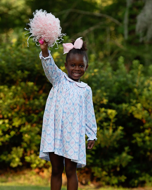 Young girl in a light blue dress with pink pom-pom in a park