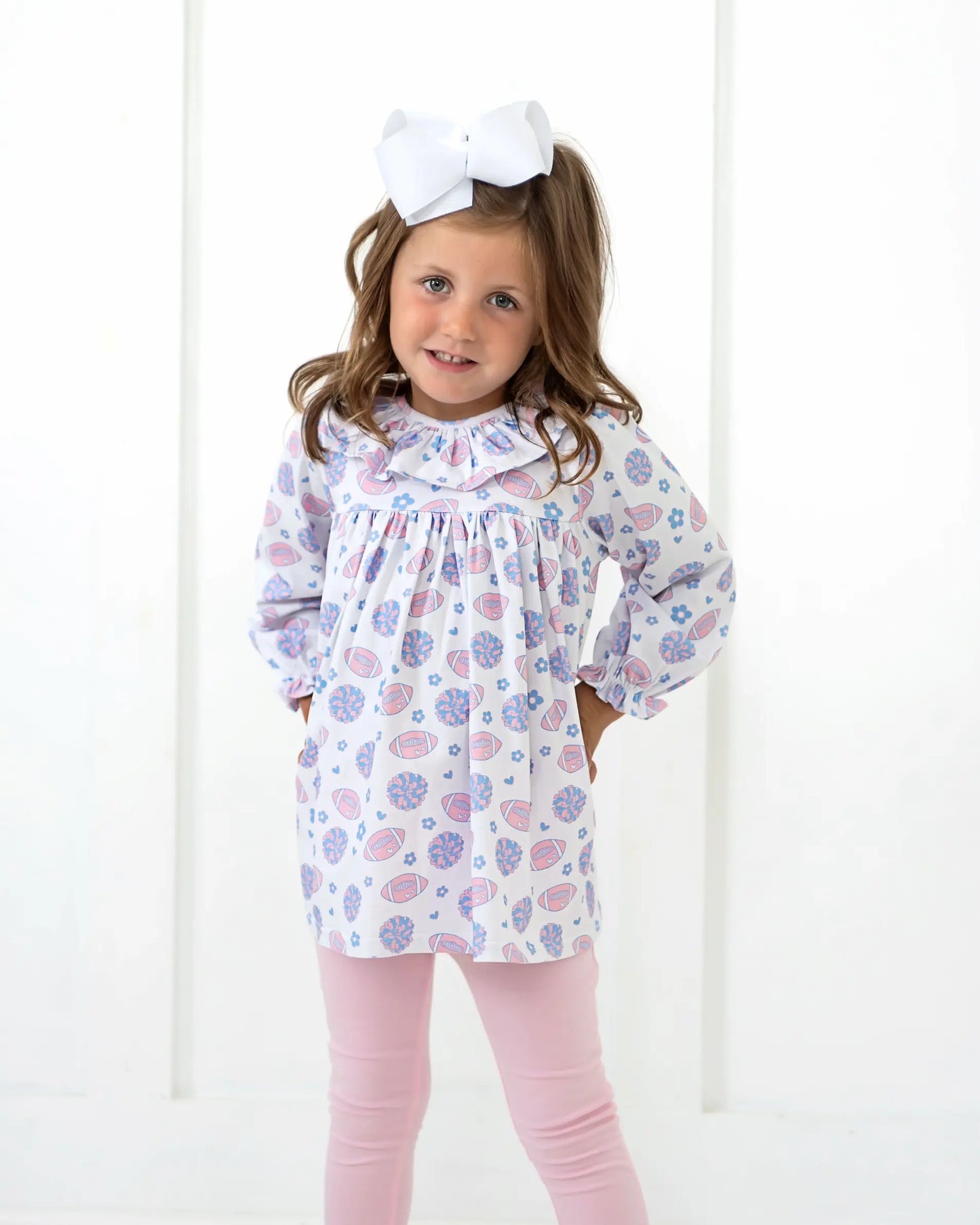 Young girl wearing a floral dress and pink leggings with a white background