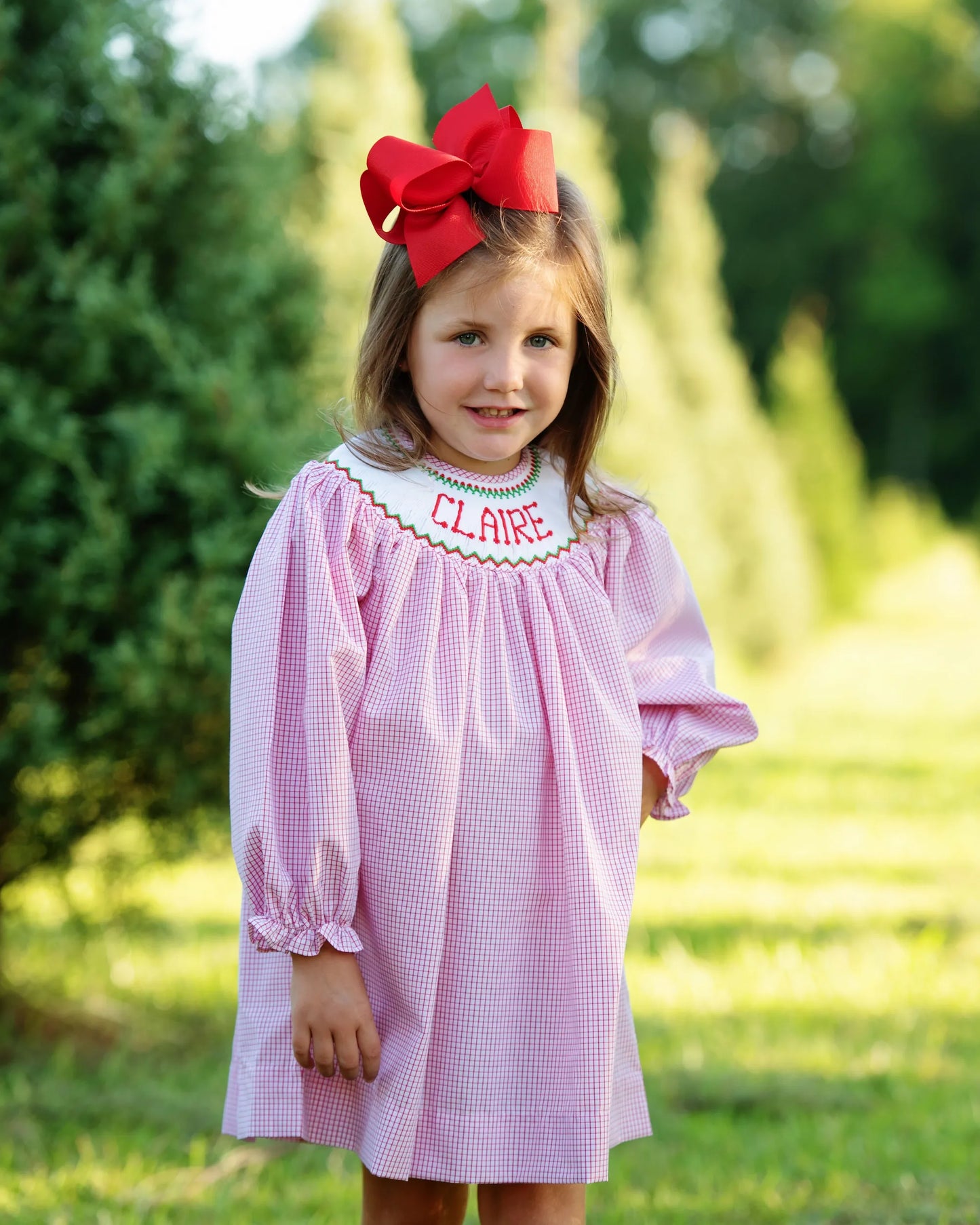 Young girl wearing a red dress with a red bow outdoors