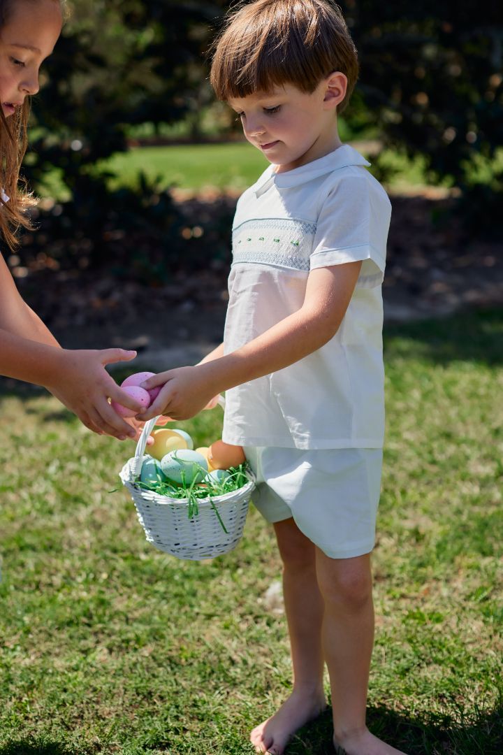 young boy holding an Easter basket, dressed in a blue and white smocked short set