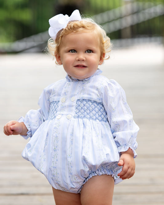 young girl wearing a blue bubble with a white bow outdoors