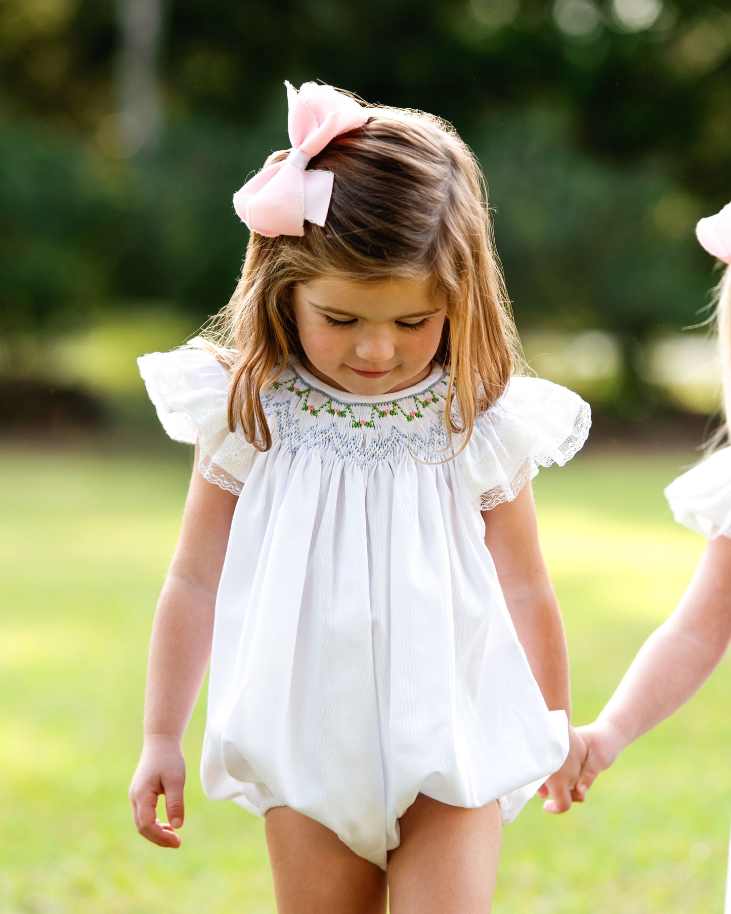 young girl wearing a smocked bubble, standing outside