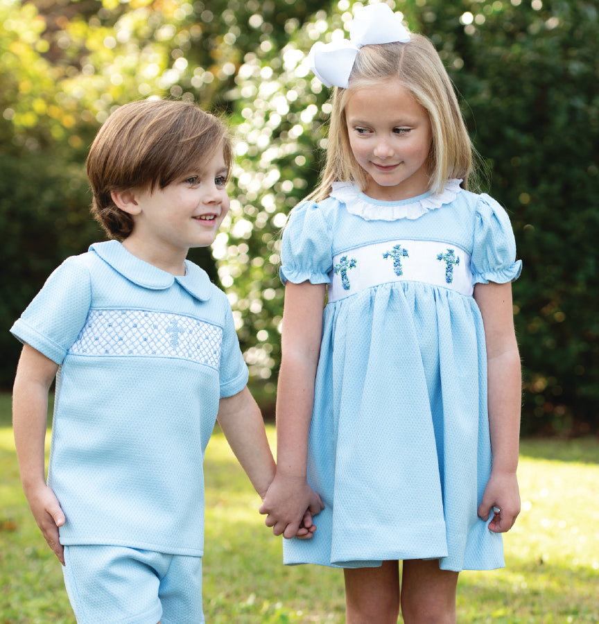 Boy and girl wearing coordinating blue smocked Easter outfits from Cecil and Lou, holding hands outdoors in classic Southern children’s clothing.