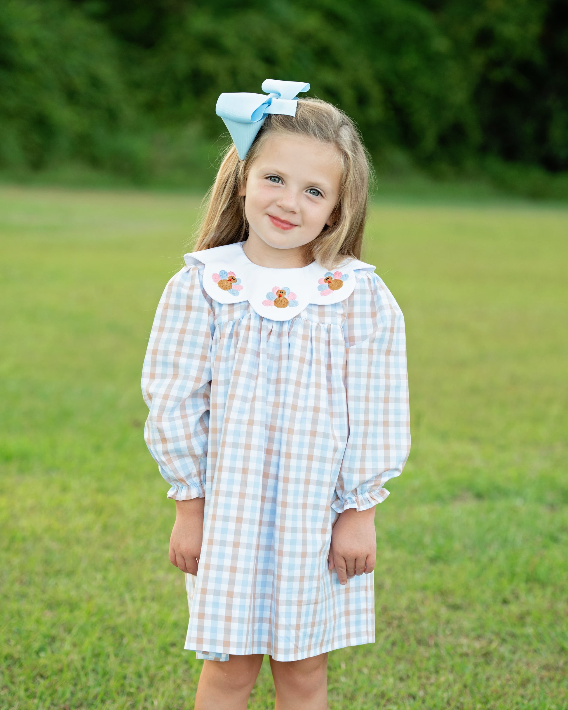 A girl wearing a blue and brown check embroidered turkeys dress