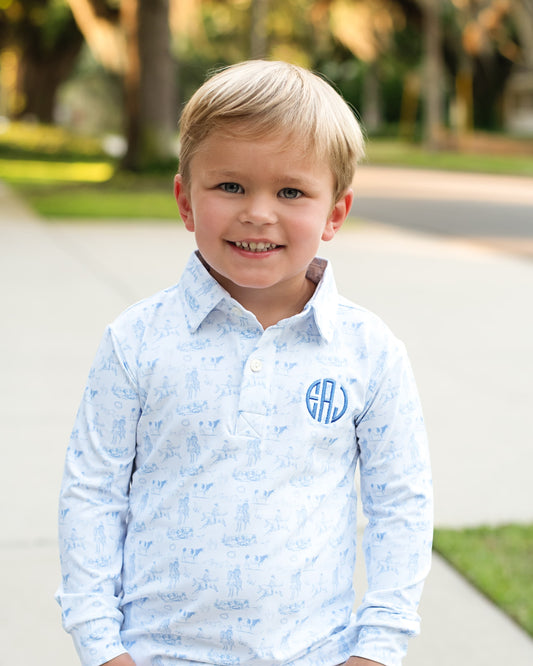 A young boy smiling wearing a cowboy themed shirt