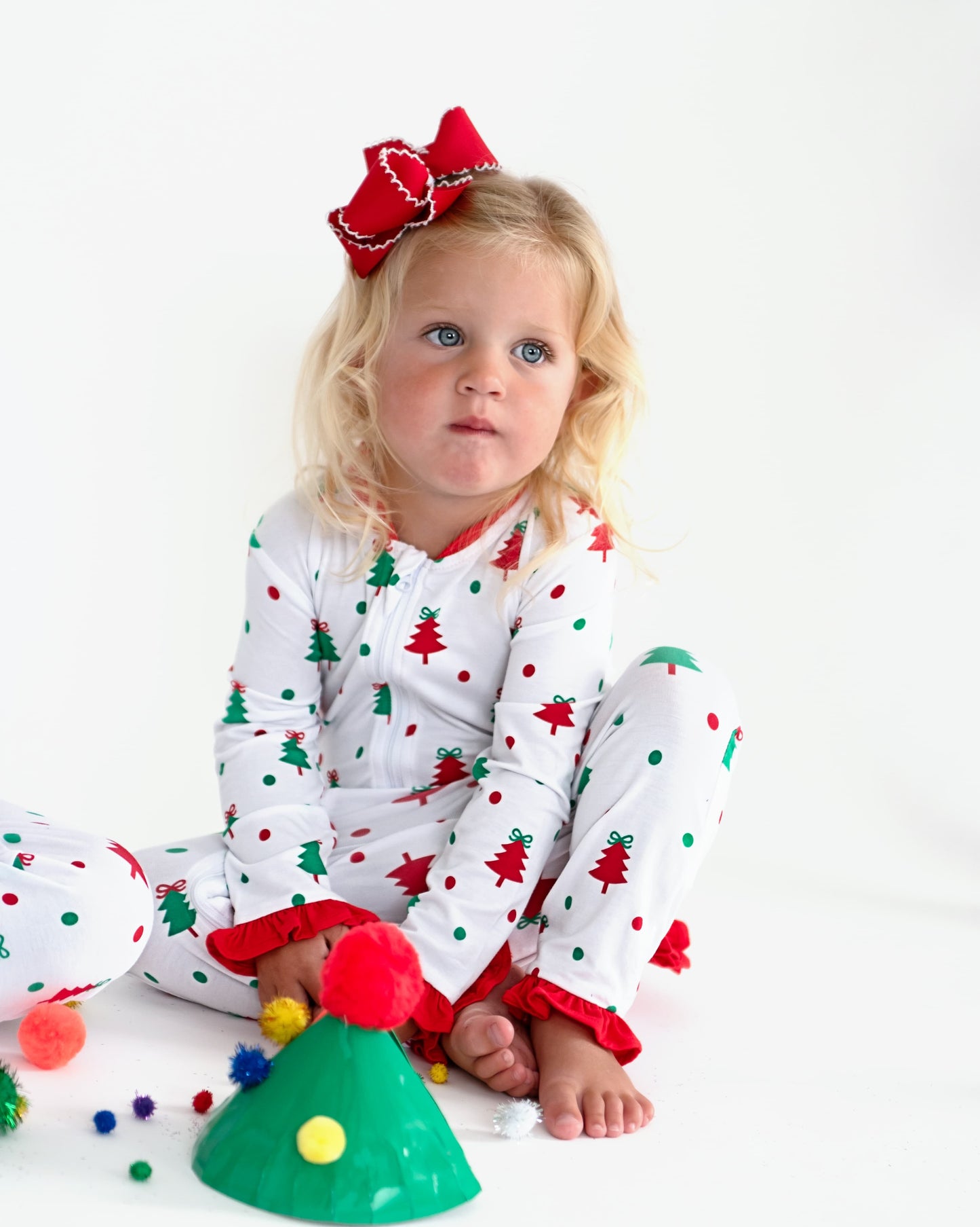 A young girl wearing Christmas pajamas making crafts.
