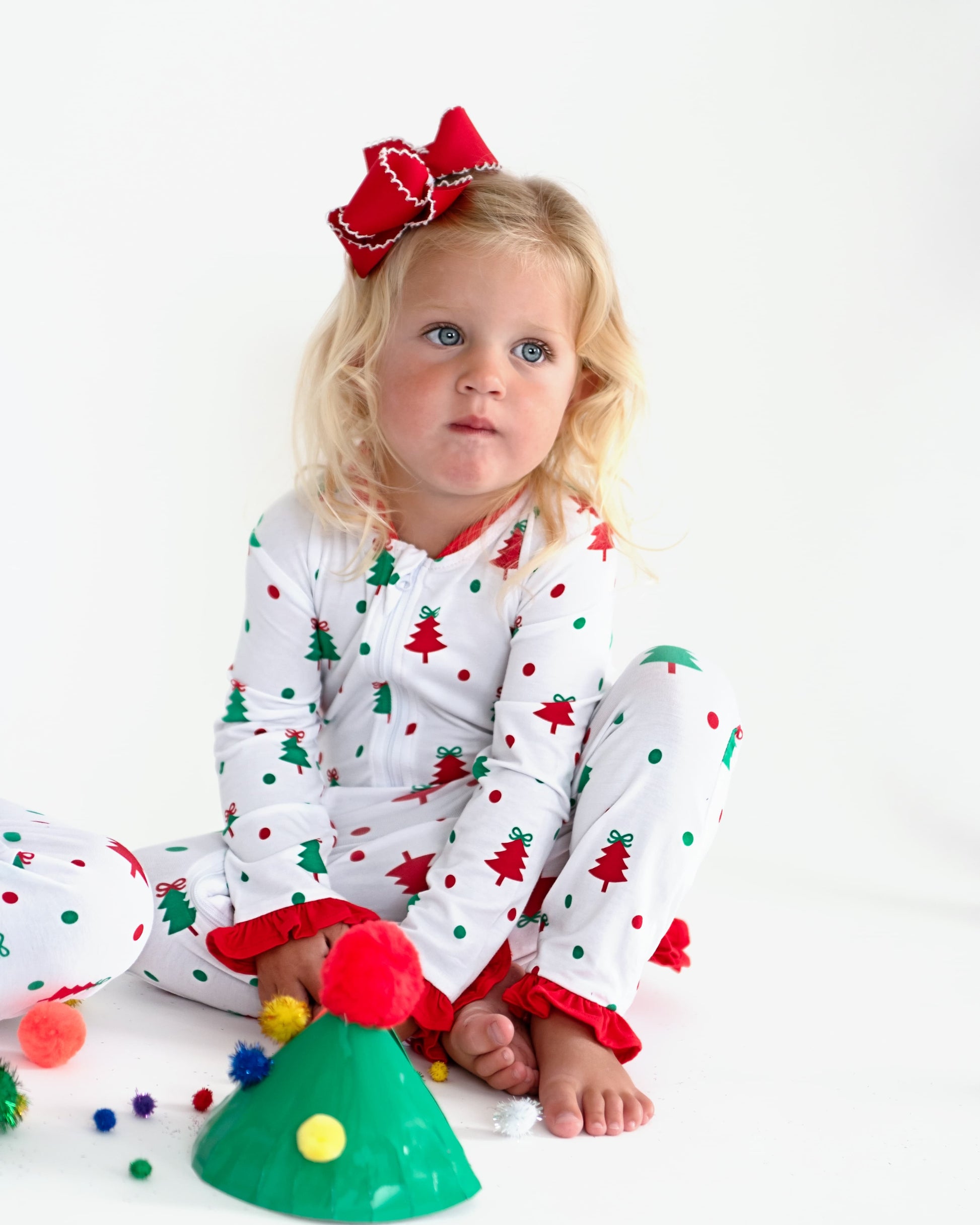 A young girl wearing Christmas pajamas making crafts.