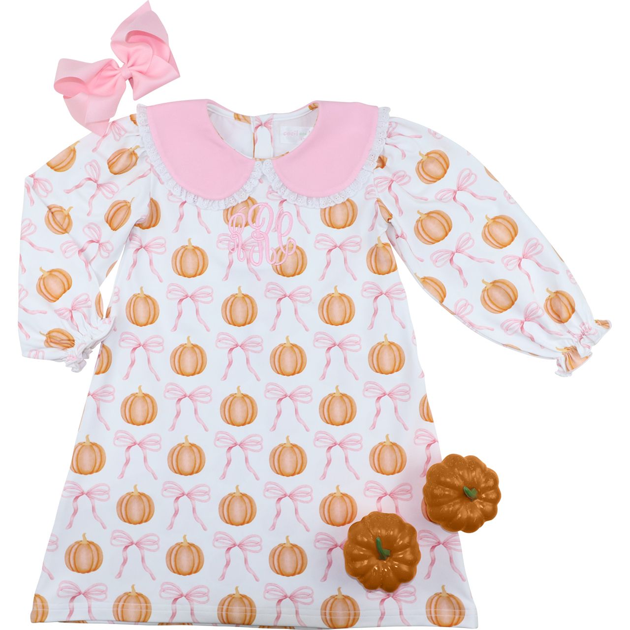 Baby dress with pumpkin and bow pattern, pink collar, and matching headband on a white background.