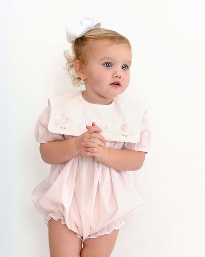 Baby girl wearing a pink outfit with a white bow on a white background
