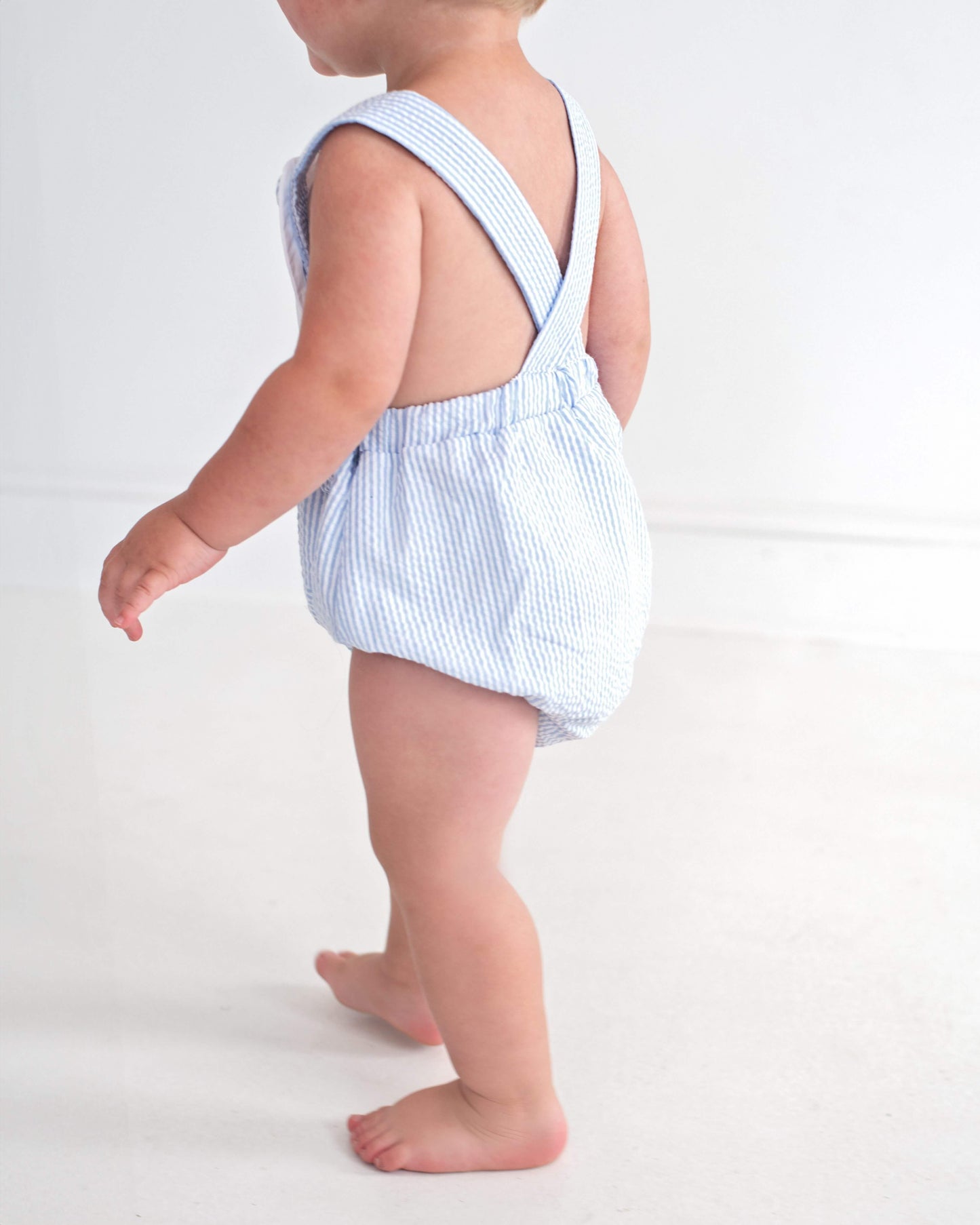 Baby wearing a blue and white striped romper on a white background
