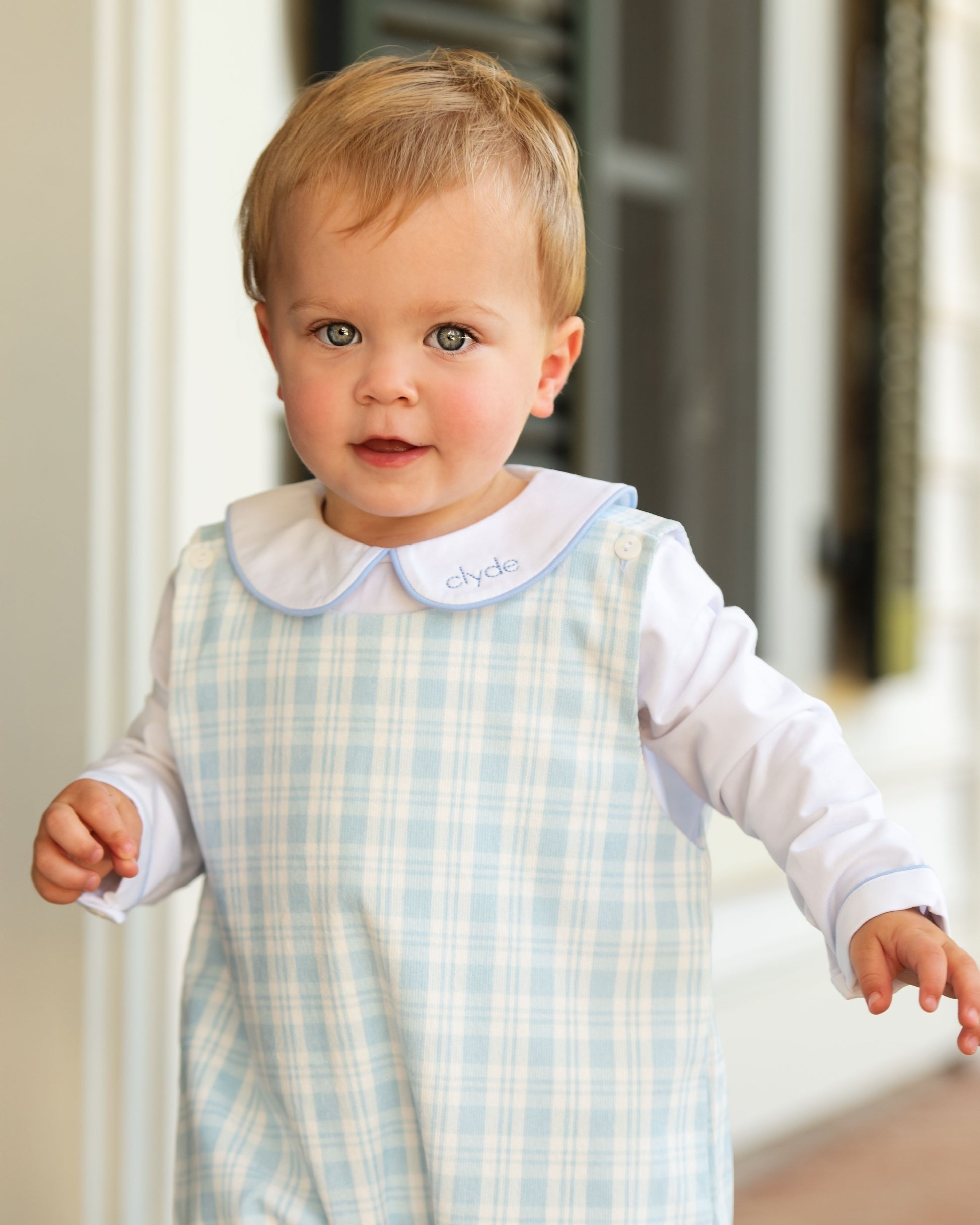 Baby wearing a checkered bib with a blurred background
