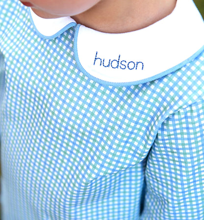Blue and green checkered bib with 'hudson' embroidered on it
