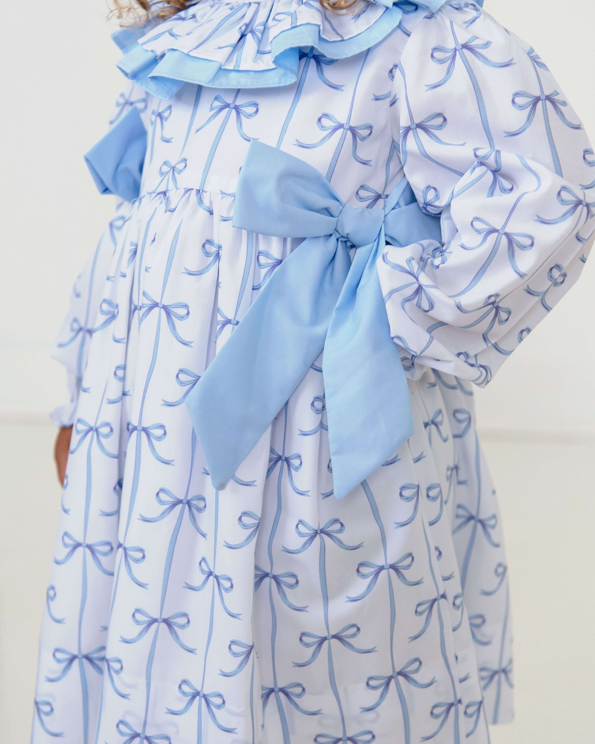 Blue and white dress with bow details on a plain background