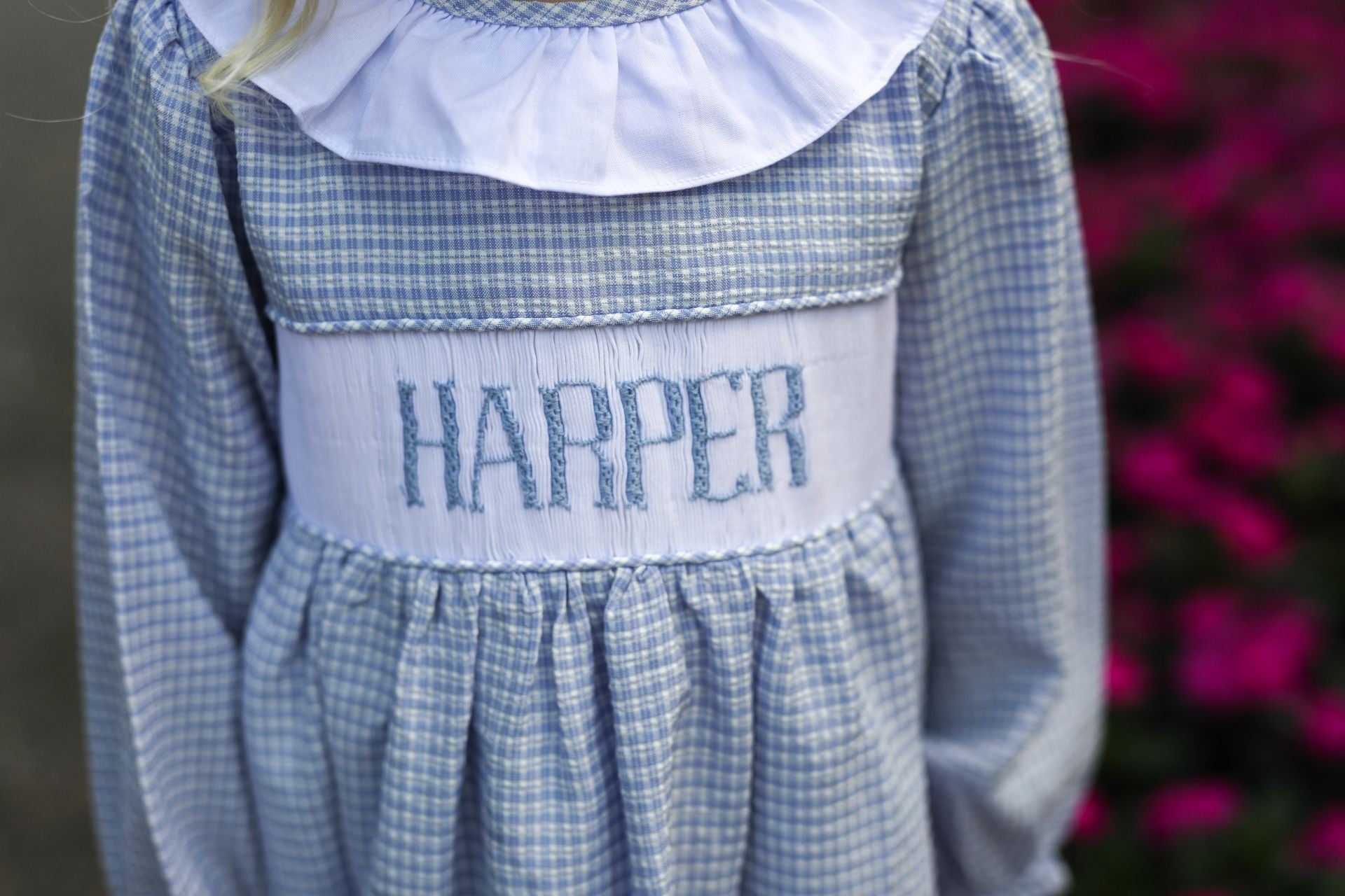 Blue checkered dress with 'HARPER' embroidery on a blurred floral background