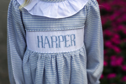 Blue checkered dress with 'HARPER' embroidery on a blurred floral background