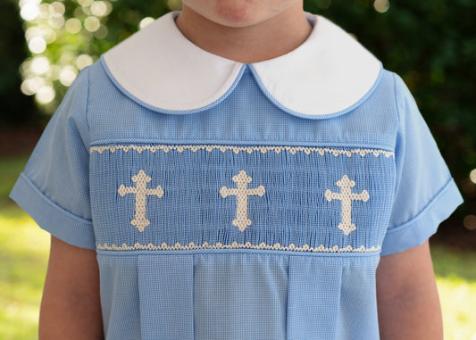 Blue outfit with white collar and cross patterns worn by a child, outdoors.