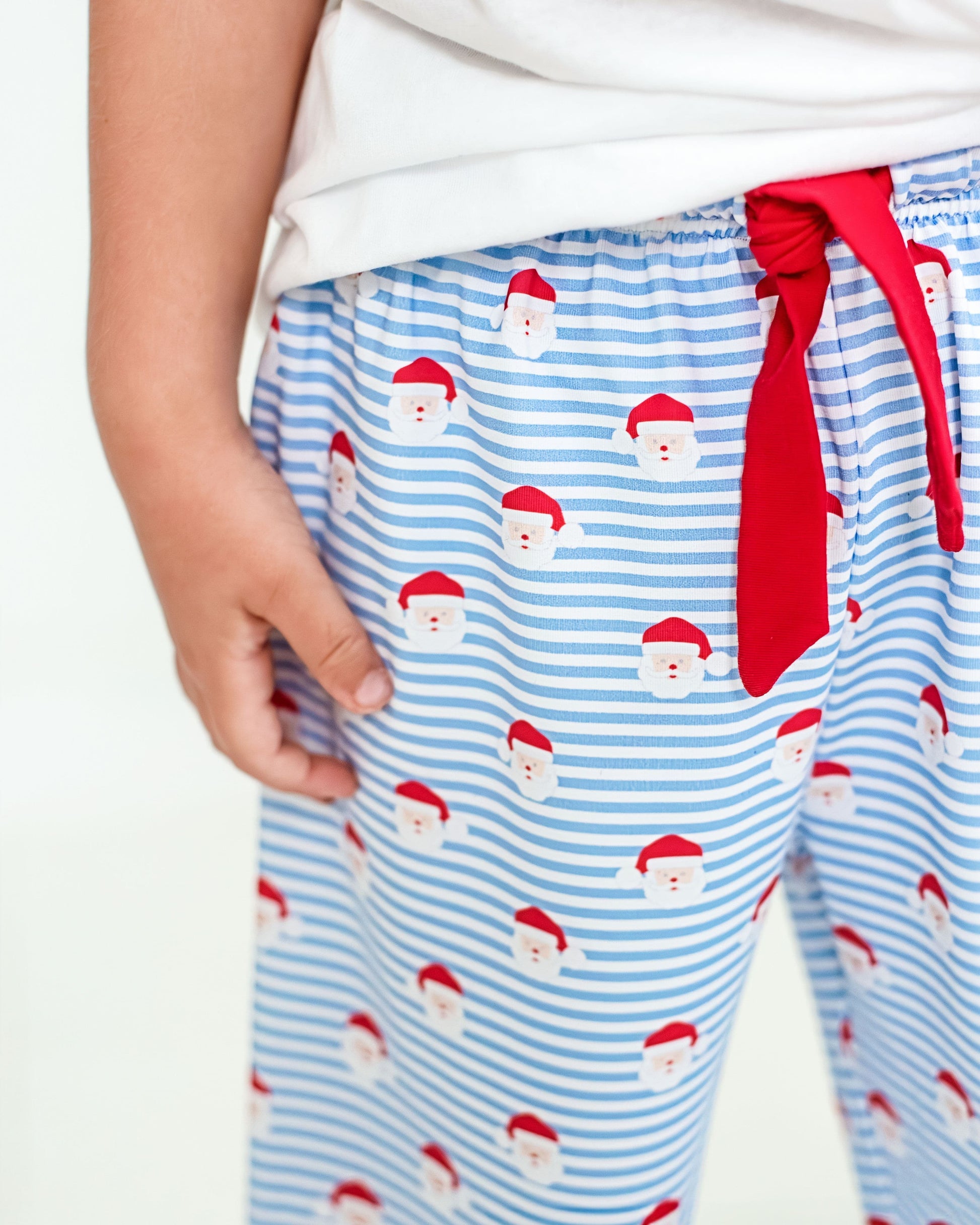Blue striped pajama pants with Santa Claus pattern and red tie on a white background