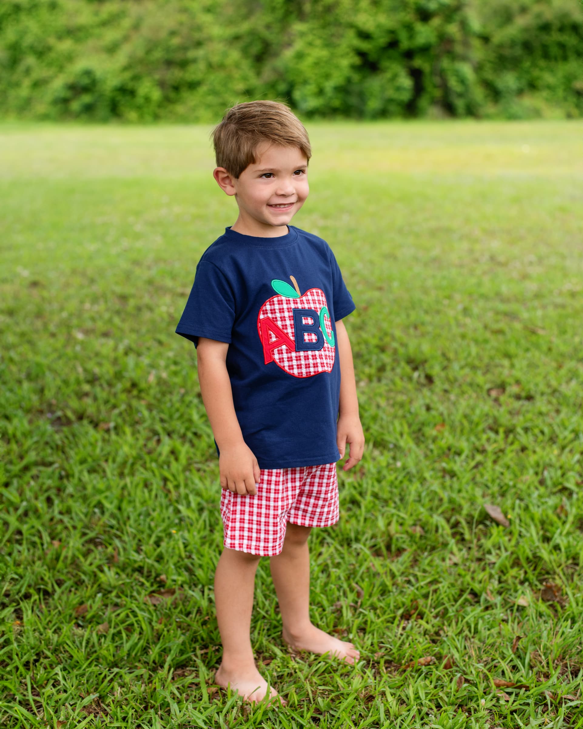 Boy in grassy field wearing an ABC outfit. 