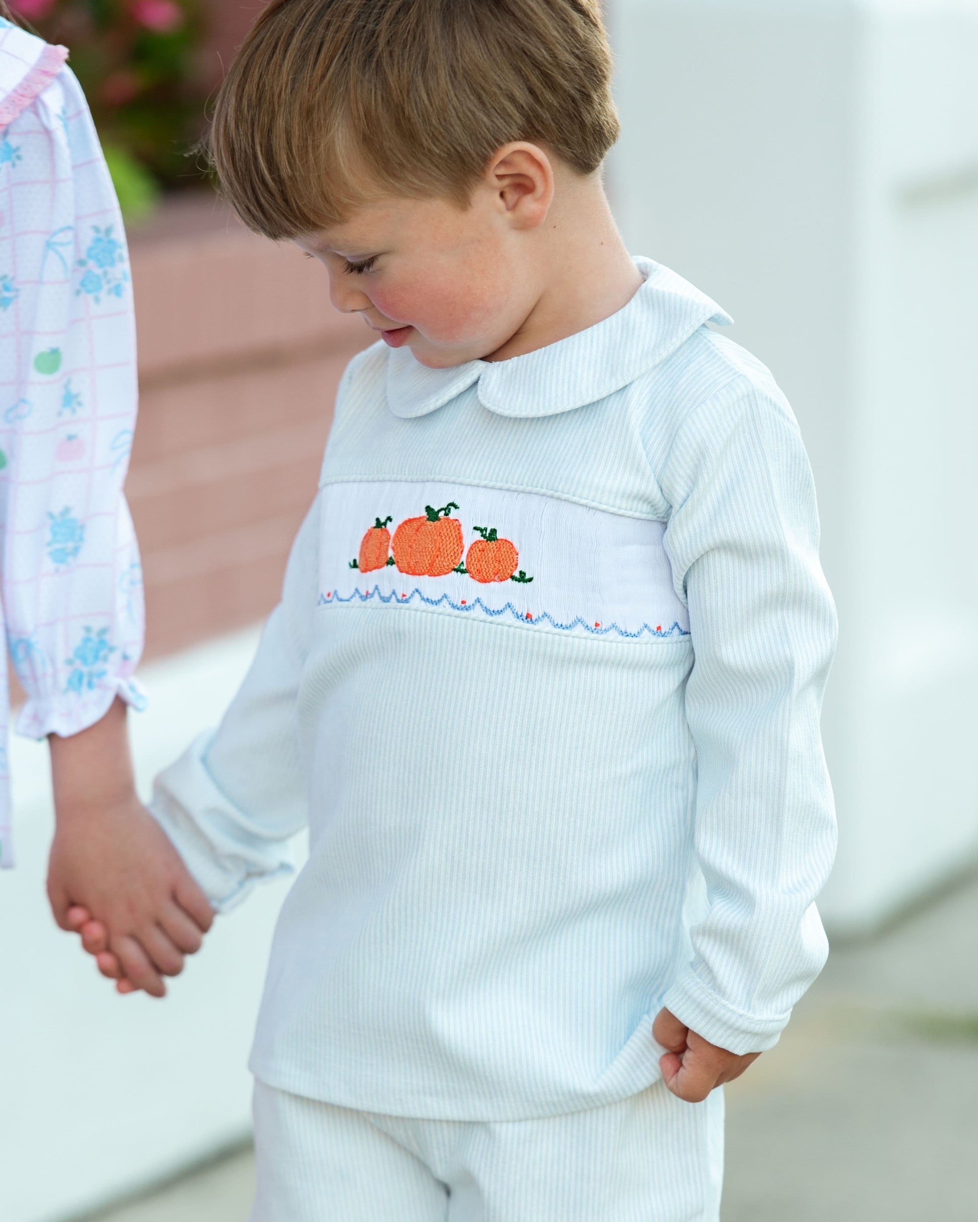 Boy wearing a blue pants set with pumpkin design outdoors