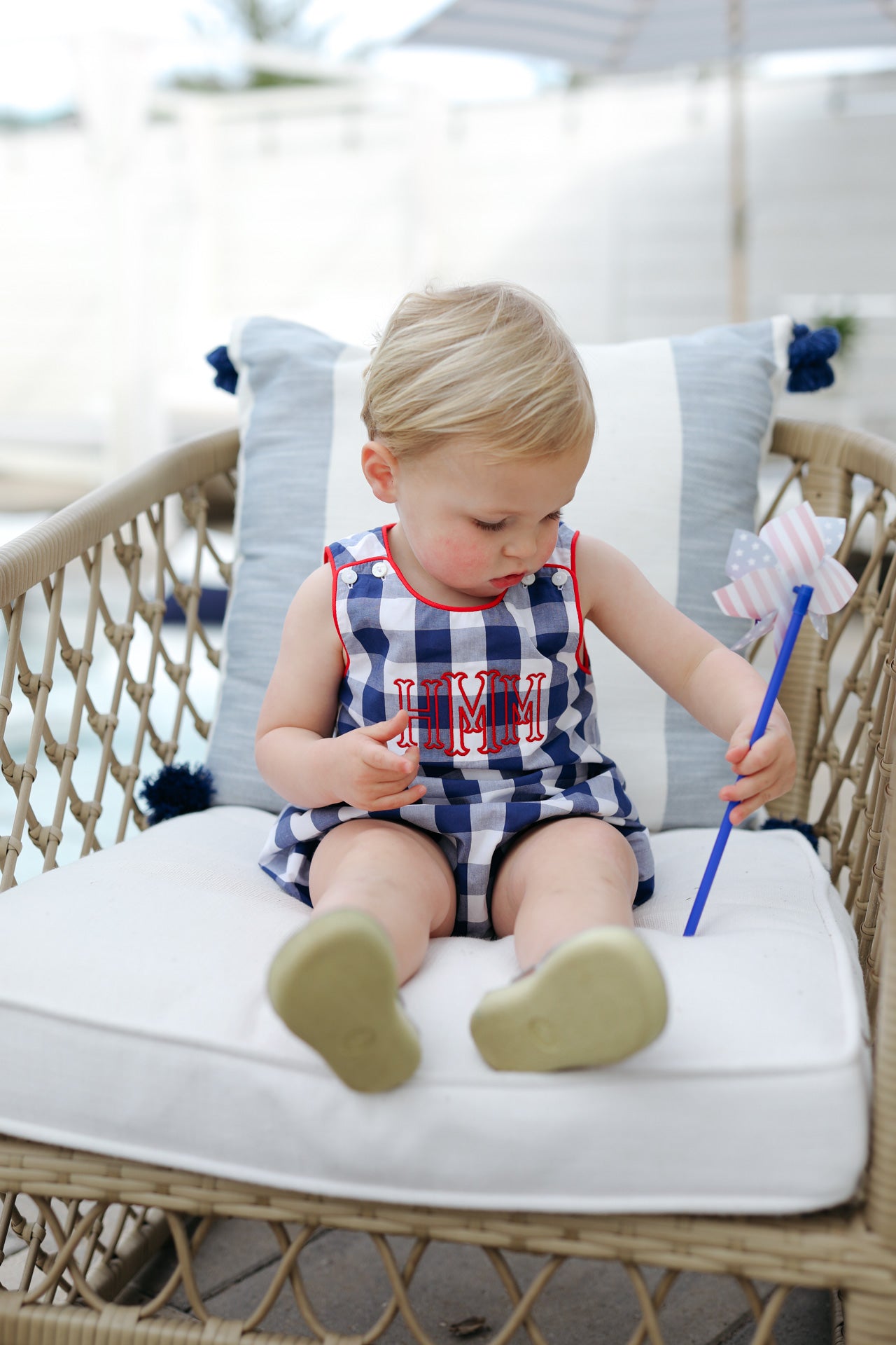 Child in a checkered bubble sitting on a wicker chair outdoors