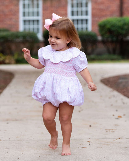 Child in a light bubble with tiny flower and a white petal collar walking outdoors.