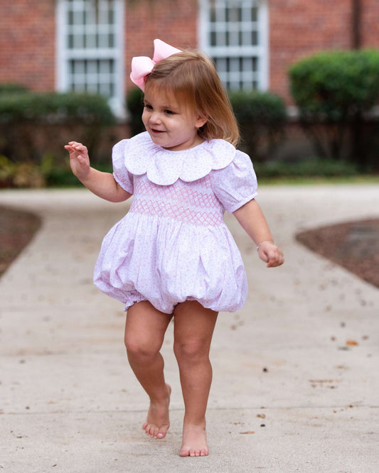 Child in a light bubble with tiny flower and a white petal collar walking outdoors.