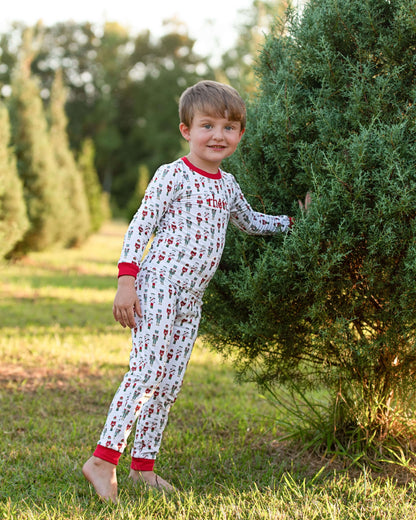 Child in pajamas standing next to a tree at a Christmas tree farm