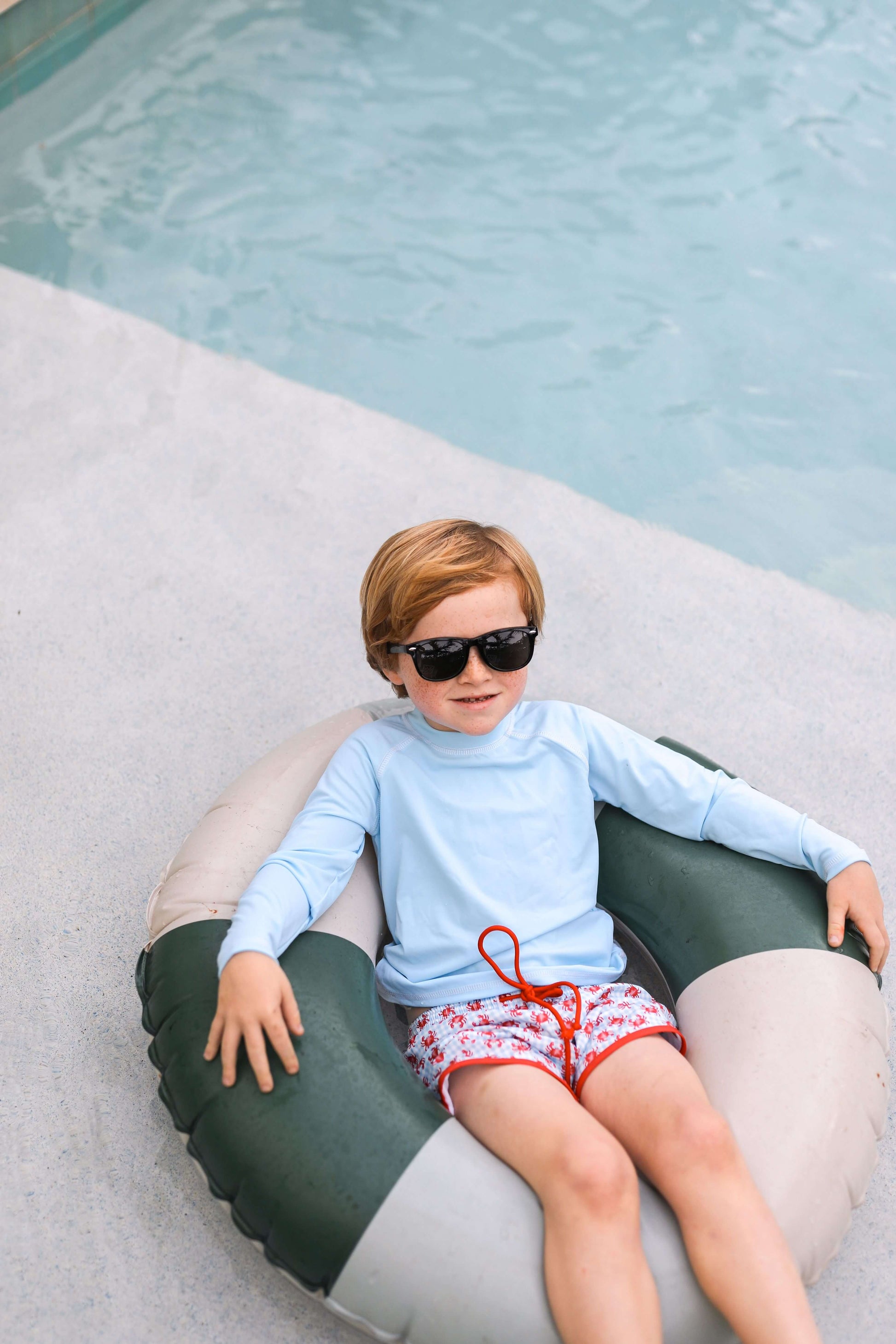 Child sitting on a pool float by a pool