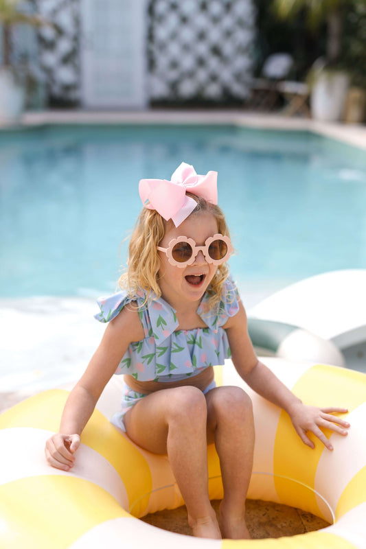 Child sitting on a yellow inflatable pool float by a pool