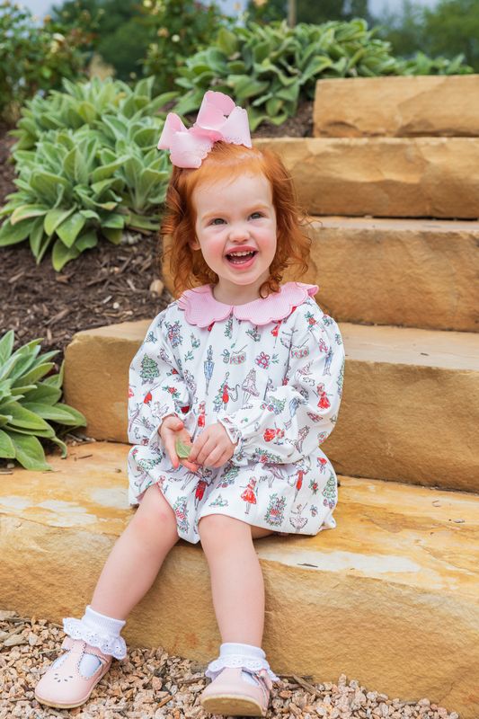Child sitting on wooden steps outdoors with a garden background