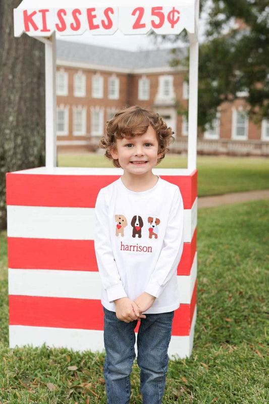 Child standing in front of a red and white striped candy stand with a sign reading 'Kisses 25 cents'.