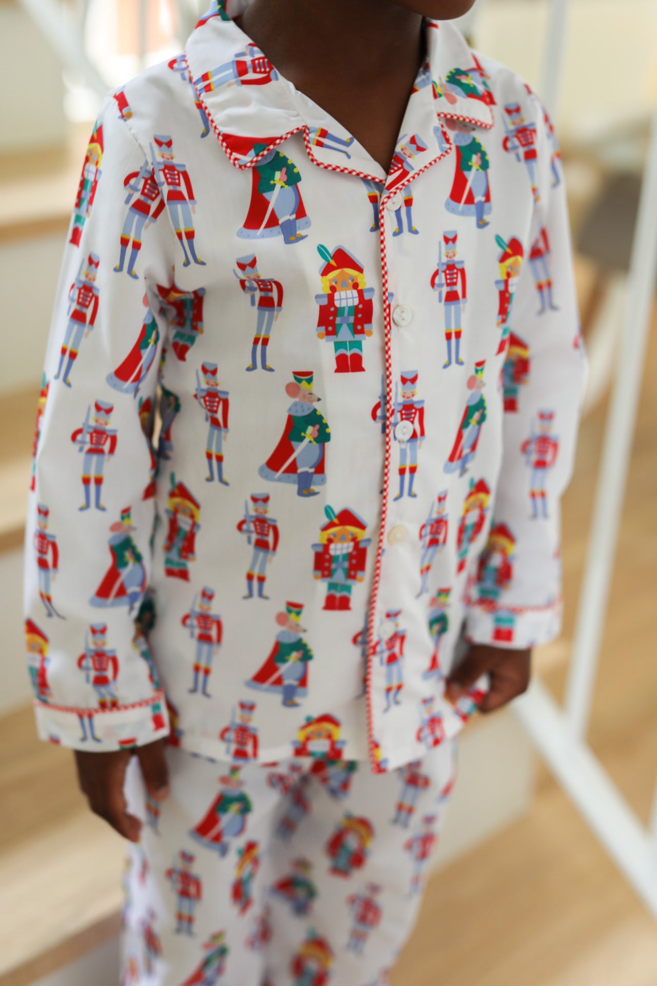 Child wearing a Nutcracker-themed pajama set on a wooden floor.
