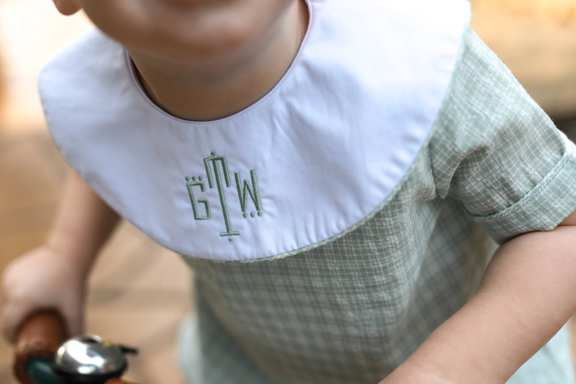 Child wearing a bib with initials 'GTV' in a green font.