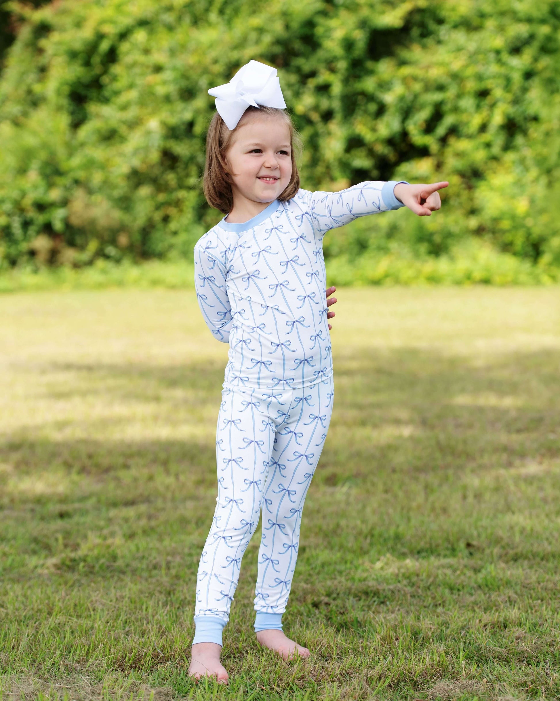 Child wearing a blue onesie with white patterns outdoors on a grassy area
