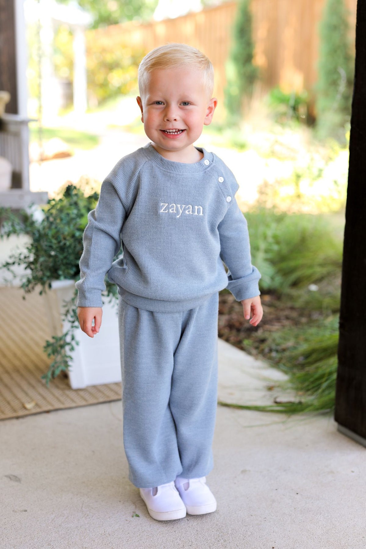 Child_wearing_a_blue_outfit_with_zayan_printed_on_it_standing_outdoors._1